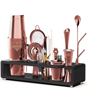 May include: Rose gold bar set with a cocktail shaker, strainer, jigger, muddler, bar spoon, and other bar tools. The set is displayed on a black stand with the text "Prodigy Mix" on the shaker.