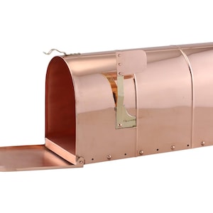 May include: A copper mailbox with a hinged door and a brass latch. The mailbox is made of polished copper and has a shiny finish.
