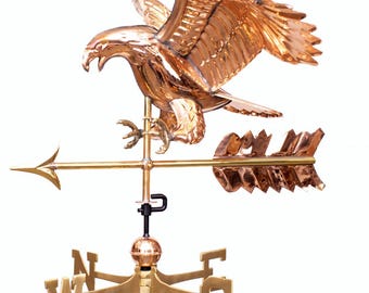 Puede incluir: Una veleta de color cobre que representa un águila detallada con las alas extendidas, posada sobre una flecha direccional. La veleta incluye los puntos cardinales y una esfera decorativa, todo montado sobre un poste negro. Altura total aproximada 76 cm.