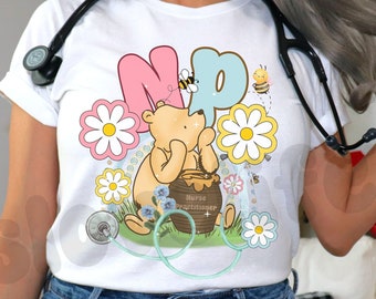 May include: White, light blue, and pink t-shirts with a Winnie the Pooh design and the text "NP" for Nurse Practitioner. The shirts feature a stethoscope and floral accents.