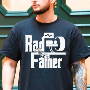 May include: A black t-shirt with a white graphic design that says "Rad-D Farmer" with a skeleton figure sitting on a bar.