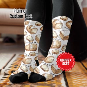 May include: White socks with a repeating pattern of illustrated sourdough bread loaves. The socks have black heels and toes. Text on the socks reads "sourdough hoo". A red badge reads "UNISEX SIZE". The text "Plain or Custom Text" is also visible.