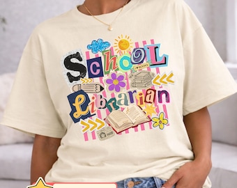 May include: Cream-colored t-shirt with a colorful "School Librarian" graphic. The design includes a pencil, books, flowers, and the text "I love books." The bottom of the shirt has the word "SAND" and a star with the text "ANY SCHOOL TITLE".