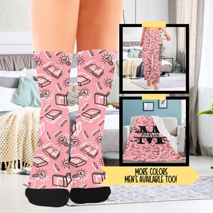 May include: Pink socks with a pattern of books, light bulbs, and pencils. The socks are shown on a person's legs. There is a pink blanket with a book pattern and the name "Maria" on it. There is also a pair of pink pajamas with a book pattern and the name "Rachel" on them. The text "More Colors Men's Available Too!" is at the bottom of the image.