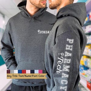 May include: Dark gray hoodie with a front pocket and a drawstring hood. The left sleeve displays "PHARMACY Tech" in white lettering. The front of the hoodie has the name "JORDAN" in white lettering. The bottom of the image shows a color palette.