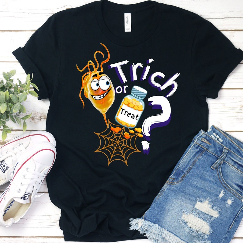 以下が含まれることがあります： ハロウィーンをテーマにしたグラフィックがプリントされた黒いTシャツ。デザインは、漫画のオレンジ色の笑顔の生き物、"Treat"と書かれた瓶、クモの巣、そして"Trick or Treat"という言葉が白と紫で描かれています。