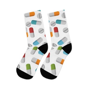 May include: A pair of white socks with a colorful pill pattern. The socks have black toes and heels.