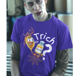 以下が含まれることがあります： ハロウィーンをテーマにしたグラフィックがプリントされた紫色のTシャツ。デザインには、オレンジ色の漫画のキャラクター、"Treat"と書かれたボトル、"Trick or Treat"の文字、疑問符、クモの巣が含まれています。