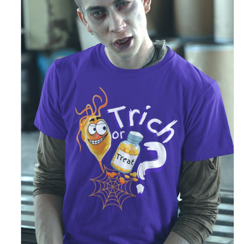以下が含まれることがあります： ハロウィーンをテーマにしたグラフィックがプリントされた紫色のTシャツ。デザインには、オレンジ色の漫画のキャラクター、"Treat"と書かれたボトル、"Trick or Treat"の文字、疑問符、クモの巣が含まれています。