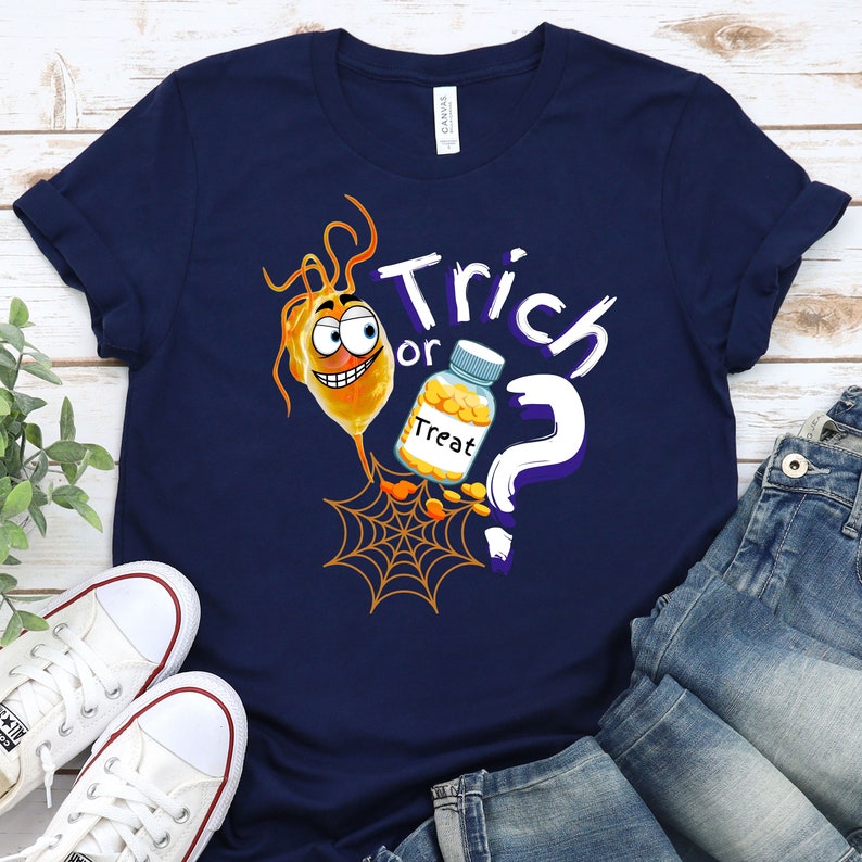 以下が含まれることがあります： ハロウィーンをテーマにしたデザインのネイビーブルーのTシャツ。デザインは、笑顔の漫画のオレンジ色の細菌、"Treat"とラベルされたボトル、クモの巣、そして白い文字で"Trick or Treat"が特徴です。