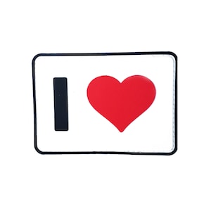 May include: A rectangular patch with the words "I" and a red heart symbol on a white background. The patch has a black border and is likely an iron-on or sew-on patch.
