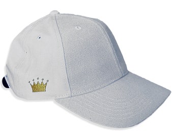 May include: A white baseball cap with a gold embroidered crown on the front.