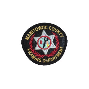 May include: Black and gold embroidered patch with the text "Manitowoc County Framing Department" around a five-pointed star with a red and white fire extinguisher and a wrench inside.