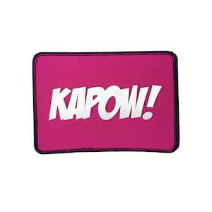 Peut inclure: Un patch rose avec des coutures noires autour des bords. Le patch a du texte blanc qui dit "KAPOW!" dans une police de caractères de style bande dessinée.