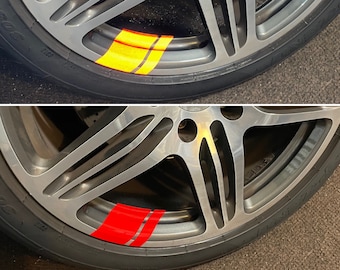 Puede incluir: Primer plano de una llanta de coche plateada con una franja de carreras roja y plateada. La franja está en el borde exterior de la llanta.