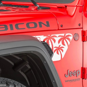 K&ouml;nnte beinhalten: Ein roter Jeep Wrangler Rubicon mit schwarzen Kotfl&uuml;gelverbreiterungen und einem Palmenaufkleber. Das Fahrzeug hat ein schwarzes "Jeep Wrangler"-Logo an der Seite.