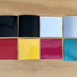 K&ouml;nnte beinhalten: Acht quadratische Muster aus verschiedenen Vinylfarben, darunter Schwarz, Wei&szlig;, Silber, Rot, Gelb, Pink und T&uuml;rkis.