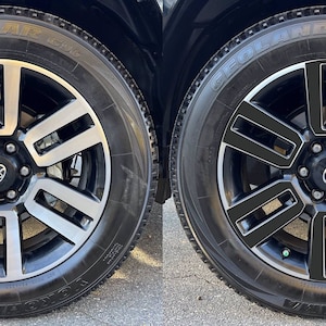 May include: Two images of a black car wheel with a silver rim. The wheel has a black center cap with a silver Toyota logo. The left image shows the wheel with a silver accent on the spokes. The right image shows the wheel with a black accent on the spokes.