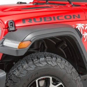 K&ouml;nnte beinhalten: Ein roter Jeep Wrangler Rubicon mit schwarzen Kotfl&uuml;gelverbreiterungen und einem Palmenaufkleber. Der Jeep hat einen schwarzen K&uuml;hlergrill und schwarze R&auml;der.