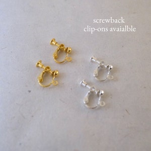 Op de afbeelding: Twee paar gouden en zilveren schroefbevestigingen voor oorbellen. De bevestigingen zijn ontworpen om te worden gebruikt met clip-oorbellen. De tekst "screwback clip-ons available" staat boven de oorbellen.