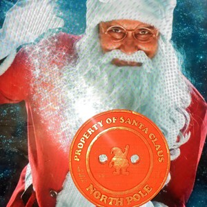 以下が含まれることがあります： 「Property of Santa Claus North Pole」と金色の文字が書かれた赤いボタン。ボタンの中央には、漫画の妖精が描かれている。ボタンは、赤いスーツを着て白いひげを生やしたサンタクロースが持っている。
