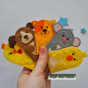 Könnte beinhalten: Eine Sammlung bunter Fingerpuppen aus Filz in Form eines Hundes, einer Katze, einer Maus und zwei Küken. Die Puppen sind gelb, orange, braun und grau mit gestickten Details. Der Text "PDF PATTERN" ist sichtbar.