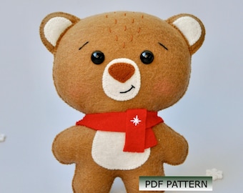 May include: A handmade brown teddy bear with a red scarf featuring a white star. The bear has black button eyes, a brown nose, and white accents on its ears and belly. The text "PDF PATTERN" is visible.