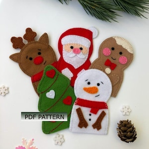 May include: A collection of felt Christmas ornaments, including a reindeer, Santa Claus, a Christmas tree, a snowman, and a gingerbread man. The ornaments are in various colors, including red, green, brown, and white. The text "PDF PATTERN" is visible.