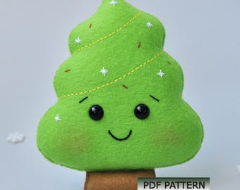 Könnte beinhalten: Ein grüner Weihnachtsbaum aus Plüsch mit einem lächelnden Gesicht, schwarzen Knopfaugen und einem braunen Sockel. Der Baum ist mit weißen Sternakzenten und gelben Nähten verziert. Der Text "PDF PATTERN" wird auf dem Sockel angezeigt.