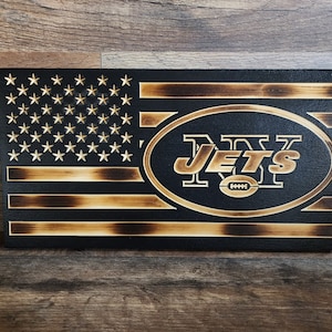 Könnte beinhalten: Eine amerikanische Holzflagge mit einem verbrannten Holzeffekt. Die Flagge hat im Zentrum ein Logo der New York Jets.