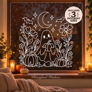 Puede incluir: Un adhesivo de ventana de arte lineal blanco con un fantasma central que sostiene una calabaza, rodeado de flores, estrellas, una luna creciente y dos calabazas adicionales. Una insignia circular muestra el texto INCLUDES 3 DIFFERENT SIZES.
