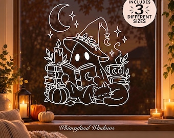 May include: A white window decal featuring a ghost wearing a witch hat, reading a book, with a sleeping cat, a pumpkin, a candle, and a crescent moon. The design includes a circular badge that reads INCLUDES 3 DIFFERENT SIZES.