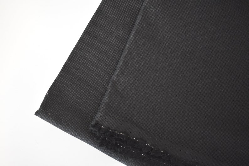 Peut inclure: Tissu Aida noir, un type de tissu utilis&eacute; pour la broderie au point de croix, avec une bordure en frange noire.
