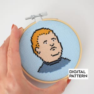 May include: A cross-stitch embroidery hoop featuring a cartoon portrait of a character with blonde hair and a blue shirt. The background is light blue. The text "DIGITAL PATTERN" is in a white rectangle.