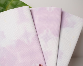 Pode incluir: Três tapetes de ioga de cor lavanda e branco com padrão tie-dye empilhados um em cima do outro.