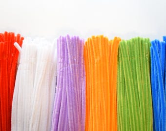 May include: A collection of fuzzy pipe cleaners arranged in vertical bundles, featuring a vibrant spectrum of colors including red, white, lavender, orange, lime green, and blue. Each individual stem has a soft, textured, and flexible surface.