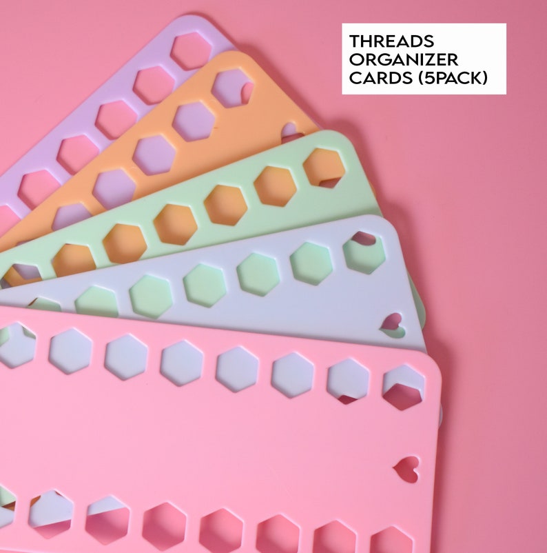 K&ouml;nnte beinhalten: Ein Stapel von f&uuml;nf pastellfarbenen Fadenorganisationskarten. Jede Karte hat eine Reihe von sechseckigen Aussparungen zum Halten von F&auml;den. Die Karten sind in Rosa-, Orange-, Gr&uuml;n- und Lavendelt&ouml;nen gehalten. Der Text "THREADS ORGANIZER CARDS (5PACK)" ist sichtbar.