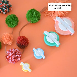 Puede incluir: Un conjunto de cuatro fabricantes de pompones de colores, de diferentes tamaños. Los fabricantes están hechos de plástico y tienen un centro blanco con una ranura para hilo. El conjunto también incluye una cadena de pompones de colores.