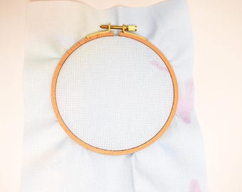 May include: A white embroidery hoop with a wooden frame, ready for cross-stitch or needlepoint projects.