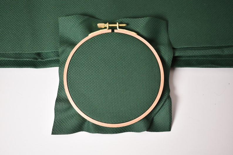 Op de afbeelding: Een groene borduurring met een houten frame. De ring is leeg en klaar om te borduren.