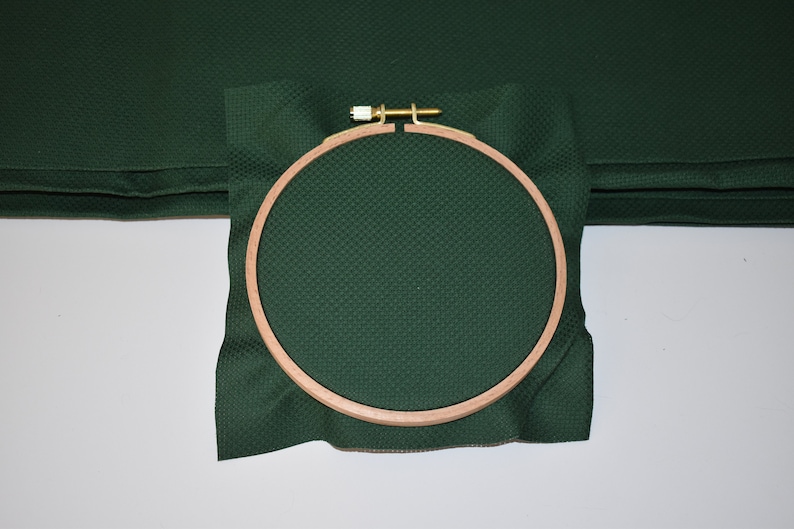 Op de afbeelding: Een groene stof gespannen over een ronde houten borduurring. De ring heeft een diameter van ongeveer 20 cm.