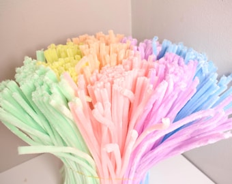 May include: A large bundle of fuzzy pipe cleaners in a variety of pastel colors including mint green, pale yellow, peach, soft pink, lavender, and light blue. The flexible craft stems are gathered together and secured with a thin wire band.