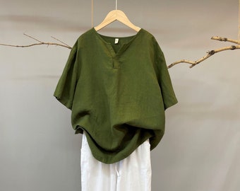 May include: A green linen shirt with a v-neck and short sleeves, paired with white linen pants.