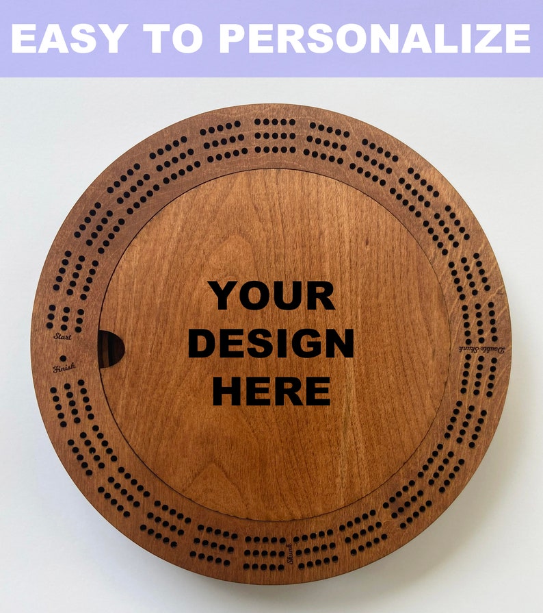 May include: A wooden cribbage board with a circular design. The board has a center section that can be personalized with a design. The text "YOUR DESIGN HERE" is printed on the board.