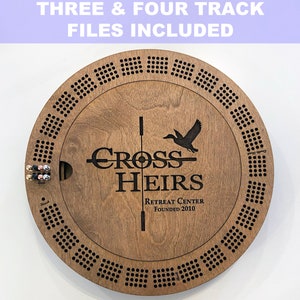May include: A wooden game board with a circular design. The board has a black and white design with a duck and the words "Cross Heirs Retreat Center Founded 2010".