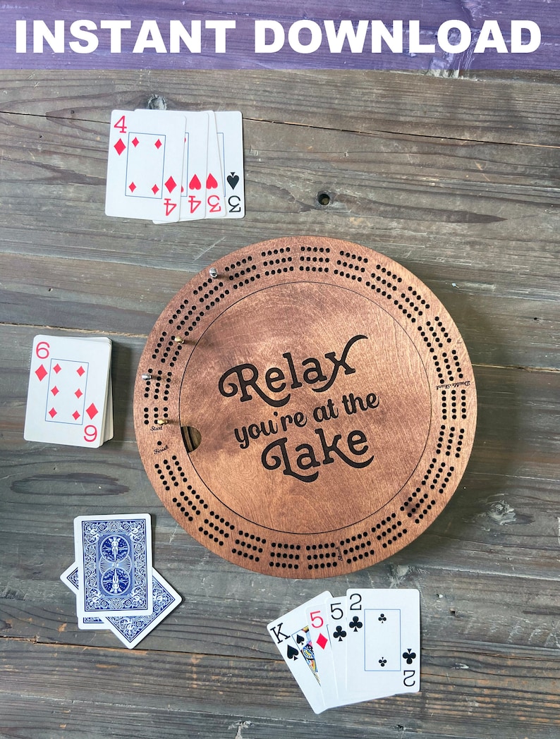 May include: A wooden cribbage board with the text "Relax you're at the Lake" on it. There are playing cards scattered around the board.