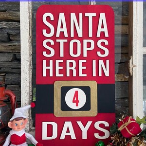 May include: Red wooden sign with white text that reads "Santa Stops Here In" and a black belt with a gold square that has a white circle with the number "4" in red. The text "Days" is below the belt in white.