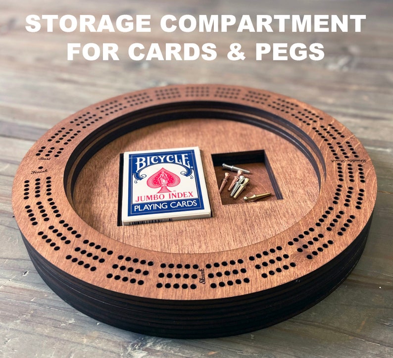 May include: A wooden cribbage board with a storage compartment for cards and pegs. The board is made of dark wood and has a circular shape. The compartment is located on the side of the board and is large enough to hold a deck of cards and a set of pegs. The board is perfect for playing cribbage with friends and family.