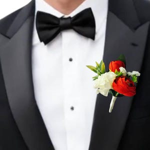 May include: A black tuxedo jacket with a black bow tie and a buttonhole of red and white flowers.