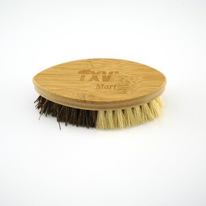 May include: An oval-shaped brush with brown and beige bristles and a bamboo handle. The handle has the text "TXV Mart" engraved on it.